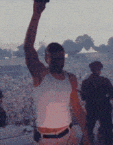 a man in a white tank top is holding a microphone up in the air