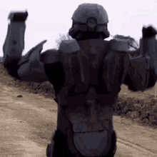 a man in a halo costume is standing in the dirt with his arms outstretched .