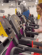 a woman is running on a treadmill in a gym with a sign that says judgment free zone