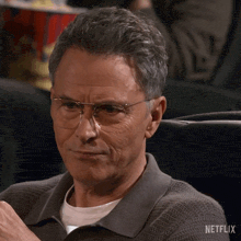 a man wearing glasses is sitting in a netflix movie theater