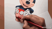 a person is drawing mickey mouse on a piece of paper with a red pencil