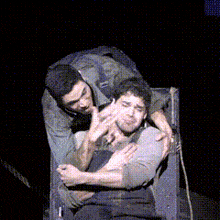 two men hugging each other on a stage in a dark room