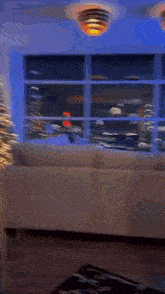 a man is standing in a living room next to a christmas tree