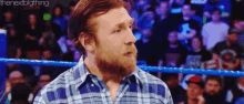 a man in a plaid shirt is standing in a wrestling ring .