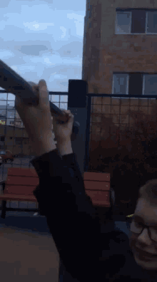 a person wearing glasses is holding a pole in a park