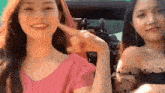 two women are sitting next to each other in a car and one is pointing at the other 's face .