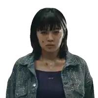 a woman wearing a purple tank top and a gray jacket looks at the camera with a serious look on her face
