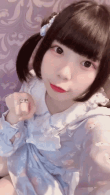 a girl with pigtails and a ring on her finger looks at the camera