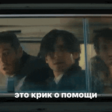 a group of men are looking out of a window with russian writing on it .