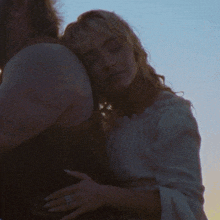 a woman wearing a ring on her finger hugs a man