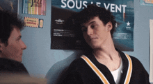 a man leans against a wall with a poster that says sous vent