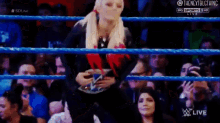 a woman is standing in a wrestling ring holding a wwe belt .