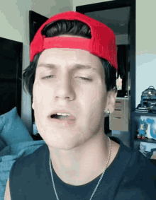 a young man wearing a red hat and a black shirt looks at the camera