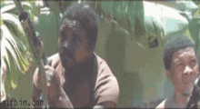 a man holding a gun with the website gifbin.com visible in the corner