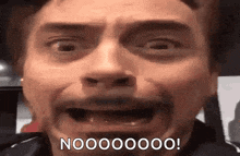 a close up of a man 's face with his mouth open and the words `` noooooo '' written on it .
