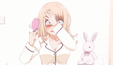 a girl brushes her hair with a pink brush in front of a stuffed rabbit