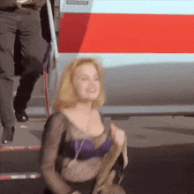 a woman in a purple bra stands in front of a red and white van that says emergency evacuation