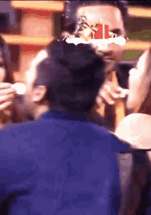 a man in a blue shirt is eating a cake with a gift box on it