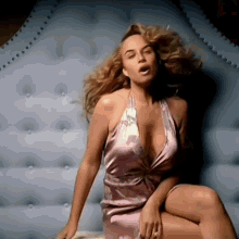 a woman in a purple dress is sitting on a bed .