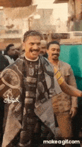 a man is getting his hair cut by a barber and smiling while standing in front of a crowd of people .