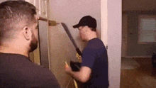 two men are standing next to each other in a room . one of the men is holding a machete .