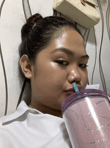 a woman is drinking from a purple cup with a blue straw