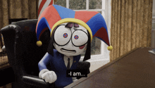 a cartoon character wearing a jester hat is sitting at a desk and says " i am "