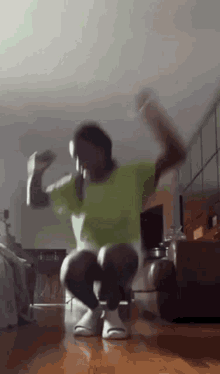 a man in a green shirt and white sandals is dancing in a living room .
