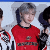 a group of young men are standing next to each other on a red carpet wearing matching jerseys .