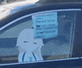 a person is sitting in a car with a sign on the window that says the a/c is on