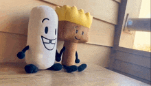 two stuffed animals are sitting on a table and one has a crown on his head