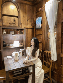 a woman sits at a table in a wooden house