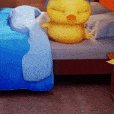 a stuffed yellow duck is sitting on a bed