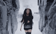 a woman in a black skirt is walking through a snowy tunnel