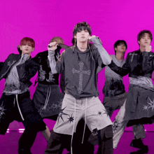 a group of young men are dancing in front of a purple backdrop