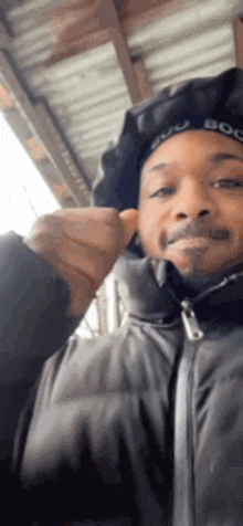 a man wearing a hooded jacket and a bandana is giving a thumbs up .