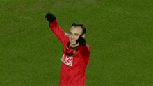 a man in a red aig jersey stands on a green field