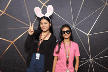 two girls posing for a picture one wearing bunny ears and the other wearing sunglasses