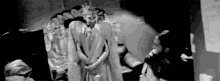 a black and white photo of a man taking a picture of two women in a room .
