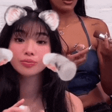 a woman with cat ears is applying makeup to another woman 's face .