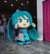 a hatsune miku doll is dancing in front of a crowd of people