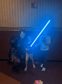 a man in a star wars costume is holding a blue light saber