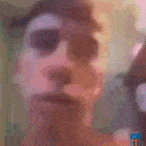 a blurry picture of a man 's face with a bottle of tnt in the background
