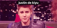 justin bieber is wearing a leather jacket and making a funny face while sitting in front of a window .