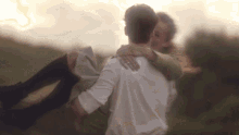 a man in a white shirt is carrying a woman in his arms in a field