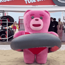 a pink teddy bear in a red bikini is holding a black tube