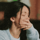 a woman covering her mouth with her hand while wearing a ring