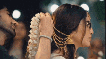 a man is putting a flower garland on a woman 's head .