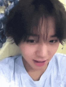 a close up of a person 's face with short hair and a white shirt