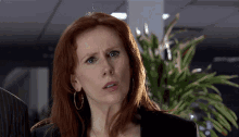 a woman with red hair and hoop earrings is looking at the camera